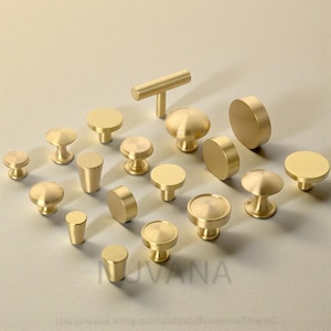 May include: A collection of various brass cabinet knobs and pulls in different shapes and sizes. The hardware includes round, cylindrical, and bar-shaped designs, all with a polished finish. The word "UVANA" is printed on the bottom of the image.