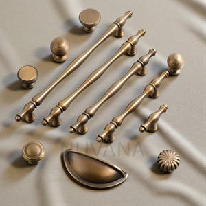 Può includere: Una collezione di ferramenta per mobili in ottone antico, tra cui pomelli, maniglie e una maniglia a tazza. L'hardware presenta un design classico con dettagli decorativi. I pezzi sono disposti su una superficie neutra.