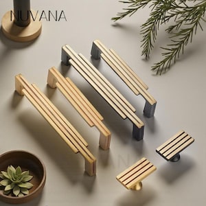 May include: A selection of gold and black cabinet handles and knobs. The handles feature a linear design with three parallel bars. The knobs have a similar design. The brand name "NUVANA" is visible in the upper left corner.