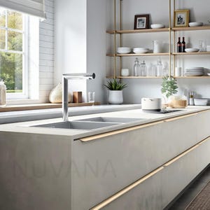 Può includere: Design moderno della cucina con un rubinetto in acciaio inossidabile sopra un doppio lavello. I mobili di colore chiaro hanno l'illuminazione integrata. Le mensole aperte espongono piatti e oggetti decorativi. La parola "NUVANA" è visibile.