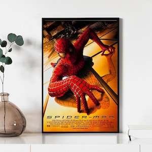 Pode incluir: Pôster de filme emoldurado com o Homem-Aranha em um traje vermelho e azul, agarrado a um prédio. O pôster tem um fundo amarelo e laranja com o título do filme "SPIDER-MAN" na parte inferior.