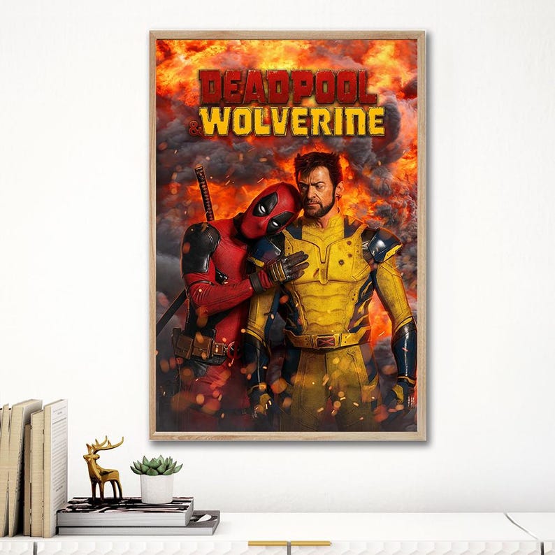 Pode incluir: Um p&ocirc;ster emoldurado com Deadpool e Wolverine. Deadpool, de fato e m&aacute;scara vermelhos, encosta em Wolverine, que usa um traje amarelo e preto. O fundo &eacute; uma explos&atilde;o de fogo com as palavras "Deadpool & Wolverine" no topo.