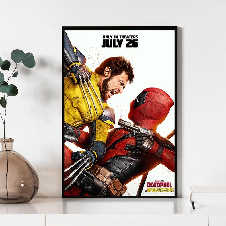 Pode incluir: Um cartaz de filme emoldurado com Wolverine em um traje amarelo e azul lutando contra Deadpool em um traje vermelho. O cartaz inclui o texto "ONLY IN THEATERS JULY 26" e o t&iacute;tulo "DEADPOOL WOLVERINE".