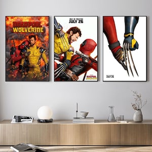 Pode incluir: Tr&ecirc;s cartazes de filmes emoldurados com Deadpool e Wolverine. Os cartazes exibem cenas de a&ccedil;&atilde;o com os personagens em seus trajes. O texto "DEADPOOL WOLVERINE" e "ONLY IN THEATERS JULY 26" s&atilde;o vis&iacute;veis.