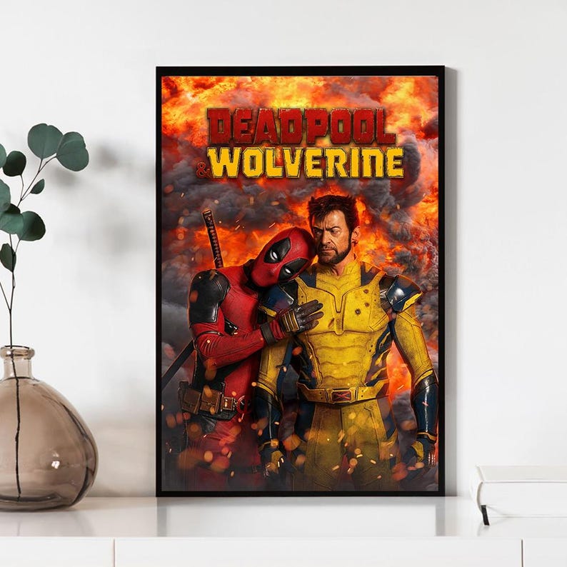 Pode incluir: P&ocirc;ster emoldurado com Deadpool e Wolverine. Deadpool, em um traje e m&aacute;scara vermelhos, abra&ccedil;a Wolverine, que est&aacute; em um traje amarelo e azul. O fundo &eacute; uma explos&atilde;o de fogo com as palavras "DEADPOOL WOLVERINE".