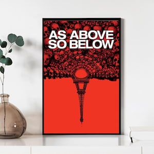 Op de afbeelding: Ingelijste kunstprint met een rode achtergrond met een zwarte illustratie van de Eiffeltoren. Boven de toren vormt een massa zwarte schedels een boog, met de witte tekst "AS ABOVE SO BELOW" bovenaan. Het kunstwerk zit in een zwarte lijst.