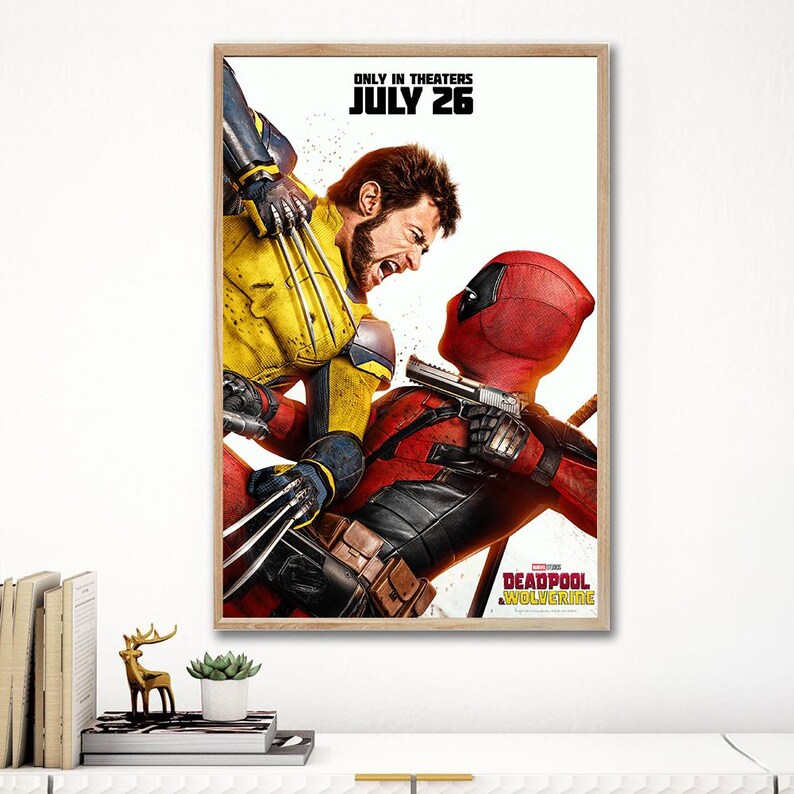 Pode incluir: Um cartaz de filme emoldurado com Wolverine em um traje amarelo e azul lutando contra Deadpool em um traje vermelho. O cartaz tem o texto "ONLY IN THEATERS JULY 26" no topo e "DEADPOOL WOLVERINE" na parte inferior.
