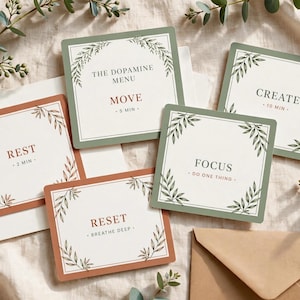 May include: A set of square cards featuring botanical leaf borders in sage green and terracotta. The cards display text including The Dopamine Menu, Move 5 min, Create 10 min, Rest 2 min, Focus Do One Thing, and Reset Breathe Deep on a cream background.