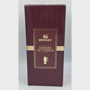 Peut inclure: Bo&icirc;te de gobelet Stanley Quencher H2.0 de couleur bordeaux. La bo&icirc;te pr&eacute;sente des lignes verticales et une &eacute;tiquette rectangulaire dor&eacute;e avec le logo Stanley et les d&eacute;tails du produit. Le gobelet contient 1,18 L.