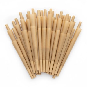 May include: A collection of pre-rolled cones made of light brown paper. The cones are cylindrical with a conical shape, and each has a small, rolled tip. The cones are arranged in a fan-like pattern against a white background.