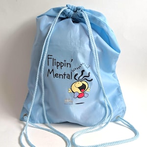 May include: Pale blue drawstring bag featuring the text "Flippin' Mental" and a cartoon character. The bag has light blue drawstrings and is made of a lightweight material.