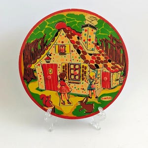 May include: A vintage, circular wooden puzzle depicting a colourful illustration of a storybook cottage with children and animals. The cottage has a red door, chimney, and polka-dot roof. The word "SIMPLEX" is visible.