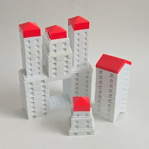 May include: A collection of white miniature building models with red roofs. The buildings vary in height and are arranged in a cluster, showcasing architectural design. The models are set against a plain white background.