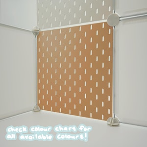 May include: A modular pegboard system featuring square panels in light beige and terracotta orange. The panels have a repeating pattern of vertical slots and are connected by white plastic corner joints. Text at the bottom reads: check colour chart for all available colours!