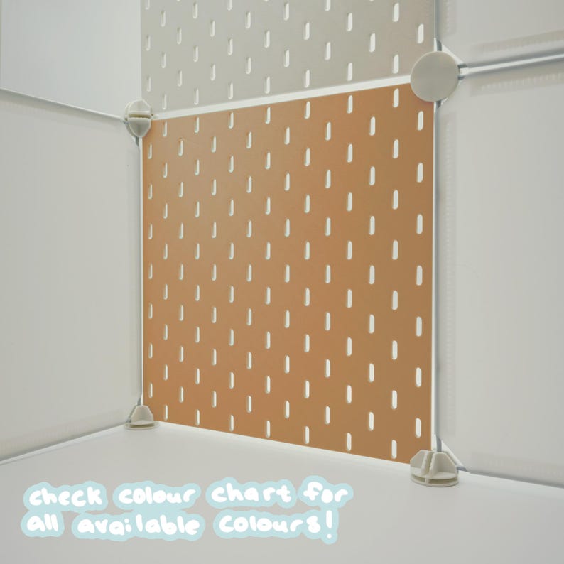 May include: A modular pegboard system featuring square panels in light beige and terracotta orange. The panels have a repeating pattern of vertical slots and are connected by white plastic corner joints. Text at the bottom reads: check colour chart for all available colours!