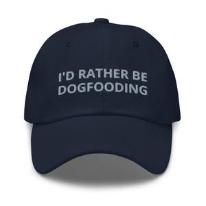 May include: A navy blue baseball cap with the text "I'd rather be dogfooding" embroidered in white on the front.