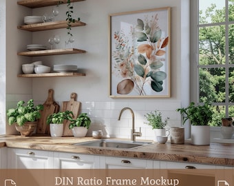 May include: A kitchen scene featuring a framed botanical print with green, brown, and peach tones. The print hangs above a sink and white cabinets. Wooden shelves hold dishes and glasses. The text "DIN Ratio Frame Mockup PSD & JPG" is at the bottom.