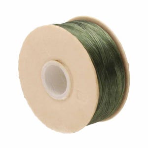 May include: A spool of dark olive green thread wound around a circular, light beige cardboard bobbin. The bobbin features a central white plastic core and a small, embossed letter B on one of its flat, circular side surfaces.