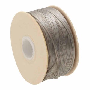May include: A spool of light gray braided cord wrapped around a circular beige cardboard core. The cord features a tight, woven texture and is wound evenly across the width of the spool, showing a consistent silver-gray color throughout.