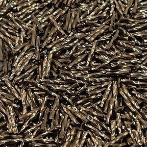 May include: A large collection of small, metallic bronze-colored bugle beads. Each bead features a distinct twisted, cylindrical shape with a reflective, faceted surface that catches the light, creating a textured appearance across the pile.