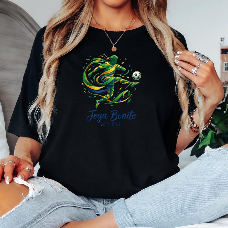 K&ouml;nnte beinhalten: Schwarzes T-Shirt mit einer dynamischen Grafik eines Fu&szlig;ballspielers in Aktion, in Gr&uuml;n, Gelb und Blau. Der Text "Joga Bonito" ist blau, darunter steht "...em brazil". Das Design f&auml;ngt die Energie des brasilianischen Fu&szlig;balls ein.