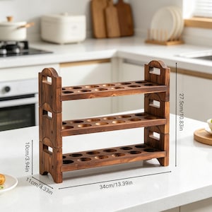 May include: A three-tiered wooden egg holder, stained in a dark brown finish. The holder has a rectangular base, with dimensions of 13.39 inches in length and 4.33 inches in width. It stands 10.83 inches tall. Each tier features multiple circular openings for egg storage.