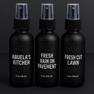 Puede incluir: Tres botellas de spray negras con tapas transparentes. Cada botella tiene una etiqueta diferente: "ABUELA'S KITCHEN", "FRESH RAIN ON PAVEMENT" y "FRESH CUT LAWN". Cada botella contiene 118 ml de producto.