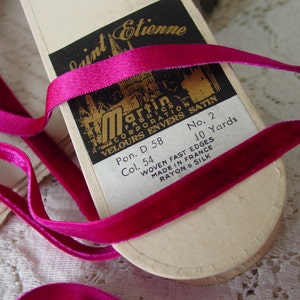 Könnte beinhalten: Eine Spule fuchsia-rosa Samtband mit dem Text "Saint Etienne Martin Fabrication Corporation Velours Envers Satin Pon. D 58 Col. 54 No. 2 10 Yards Woven Fast Edges Made in France Rayon & Silk" auf dem Etikett.