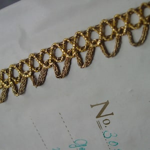 May include: Gold trim with a beaded design and a scalloped edge. The trim is on a white background.