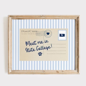 May include: Framed print featuring a vintage postcard design. The postcard reads "Meet me in State College!" in navy blue script. A blue heart and a Pennsylvania stamp are also included. The frame has a light wood finish and a blue and white striped background.