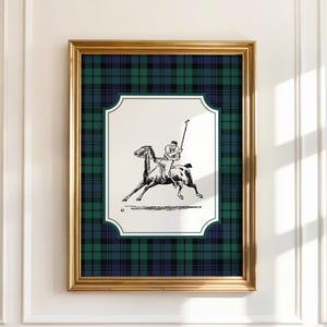 May include: Framed artwork featuring a black and white polo illustration. The artwork is set against a green and navy plaid background, framed in gold. The image depicts a polo player on horseback, swinging a mallet towards a ball.