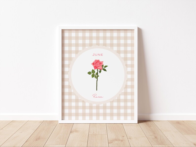 May include: A framed print featuring a pink rose illustration. The artwork is set against a beige and white checkered background. The word "June" is at the top, and "Rose" is written below the flower.