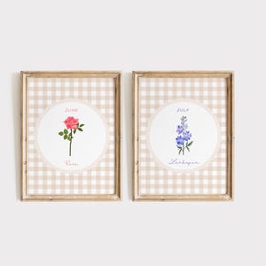 May include: Two framed floral art prints. One features a pink rose with the text "June" and "Rose." The other print displays a blue Larkspur with the text "July" and "Larkspur." Both are set against a beige gingham background.