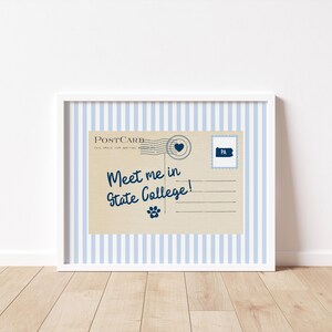 May include: A framed postcard print with a blue and white striped background. The postcard is tan with the text "Meet me in State College!" in navy blue script. A paw print and a Pennsylvania stamp are also featured.