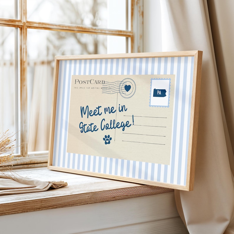 May include: A framed postcard with a light blue and white striped border. The postcard features the text "Meet me in State College!" and a paw print. A stamp with "PA" is in the upper right corner.