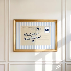 May include: A framed postcard print with a gold frame. The postcard features blue and white stripes and the text "Meet me in State College!" in blue script. A blue paw print and a heart are also visible.