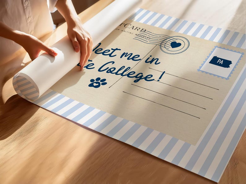 May include: A rolled-up poster with a vintage postcard design. The postcard features the text "Meet me in State College!" in navy blue script, a paw print, and a heart-shaped stamp. The border has blue and white stripes.