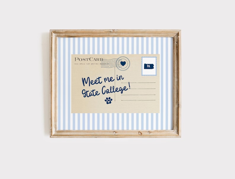 May include: Framed print featuring a vintage postcard design. The postcard reads "Meet me in State College!" in navy blue script. A blue heart and a Pennsylvania stamp are also included. The frame has a light wood finish and a blue and white striped background.
