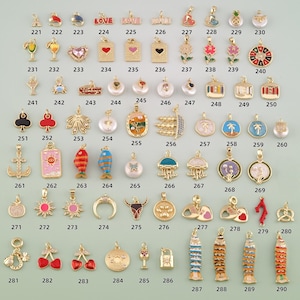 May include: A collection of gold-toned metal charms featuring various shapes including hearts, fish, flowers, palm trees, anchors, and food items, each labeled with a unique identification number from 221 to 290 for cataloging purposes.