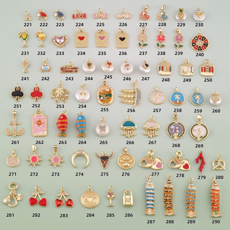 May include: A collection of gold-toned metal charms featuring various shapes including hearts, fish, flowers, palm trees, anchors, and food items, each labeled with a unique identification number from 221 to 290 for cataloging purposes.