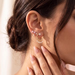 Conjunto de 3 brincos florais banhados a ouro 18K, com pingentes de flores em zircônia cúbica e borlas em formato de gota. Ideal para presente de aniversário.