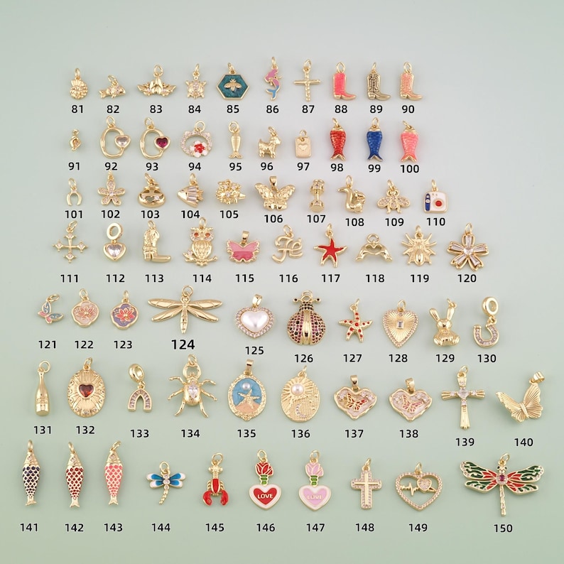 May include: A collection of gold-tone metal charms in various shapes including animals, hearts, flowers, crosses, and insects. Each charm is numbered from 81 to 150, featuring enamel details, rhinestones, and metallic finishes for jewelry making.