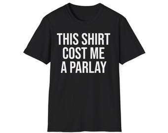 May include: Black t-shirt with white text that reads "THIS SHIRT COST ME A PARLAY." The shirt is a crew neck style and appears to be made of a soft material. The text is centered on the front of the shirt.