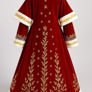 May include: A long, red velvet coat with white faux fur trim and gold embroidery. The coat features a high collar, wide sleeves, and a full skirt. Gold embroidered leaf and star patterns adorn the front and sleeves. A matching hat is also visible.