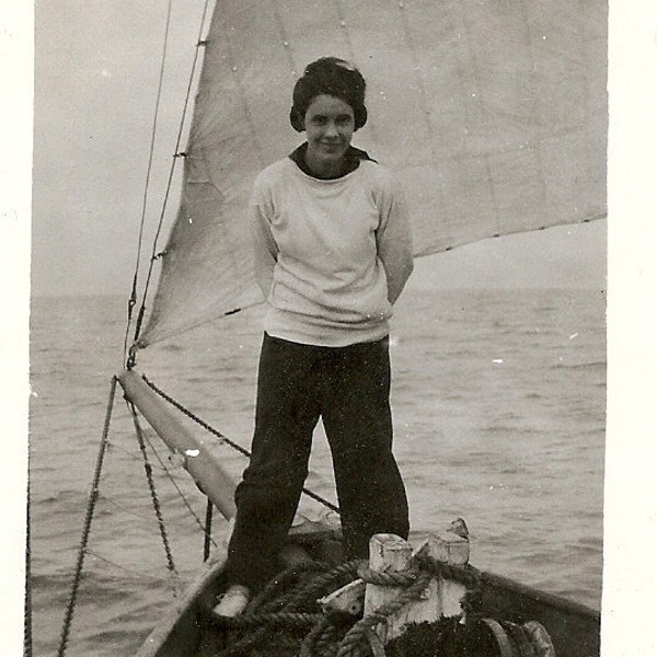 1940's photo .Woman standing on bow of sailboat