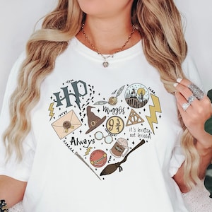 May include: White t-shirt featuring a heart-shaped design with various Harry Potter-themed illustrations. The design includes the letters "HP", a lightning bolt, a letter, a hat, glasses, and the words "Always" and "Muggles".