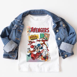 May include: A white ceramic mug with a black handle and the text "But First, Coffee" in a bold, black font. The mug is set against a blurred background, suggesting a cozy setting.