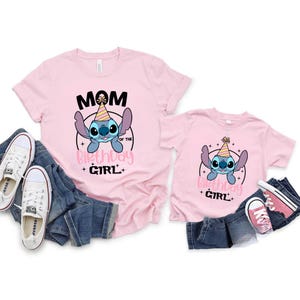 K&ouml;nnte beinhalten: Zwei rosa T-Shirts mit einem Cartoon-Charakter-Design. Das gr&ouml;&szlig;ere Shirt sagt "Mama des Geburtstagskindes" und das kleinere Shirt sagt "Geburtstagskind". Beide Shirts haben einen blauen Cartoon-Charakter mit Partyhut.