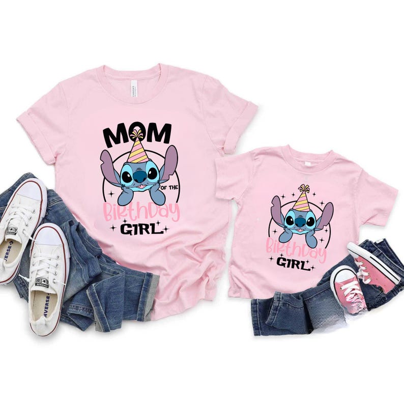 K&ouml;nnte beinhalten: Zwei rosa T-Shirts mit einem Cartoon-Charakter-Design. Das gr&ouml;&szlig;ere Shirt sagt "Mama des Geburtstagskindes" und das kleinere Shirt sagt "Geburtstagskind". Beide Shirts haben einen blauen Cartoon-Charakter mit Partyhut.