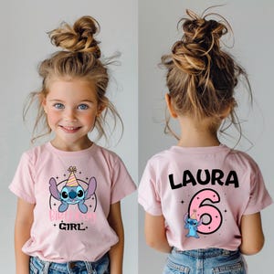 K&ouml;nnte beinhalten: Rosa kurz&auml;rmeliges T-Shirt mit einem Cartoon-Charakter-Design. Auf der Vorderseite ist ein blauer Alien mit Partyhut und den Worten "Birthday Girl" abgebildet. Auf der R&uuml;ckseite stehen der Name "LAURA" und die Zahl "6".